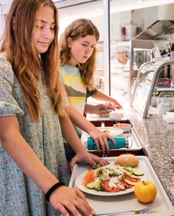 Schülerinnen holen ihr Mittagessen an der Mensa-Ausgabe ab.